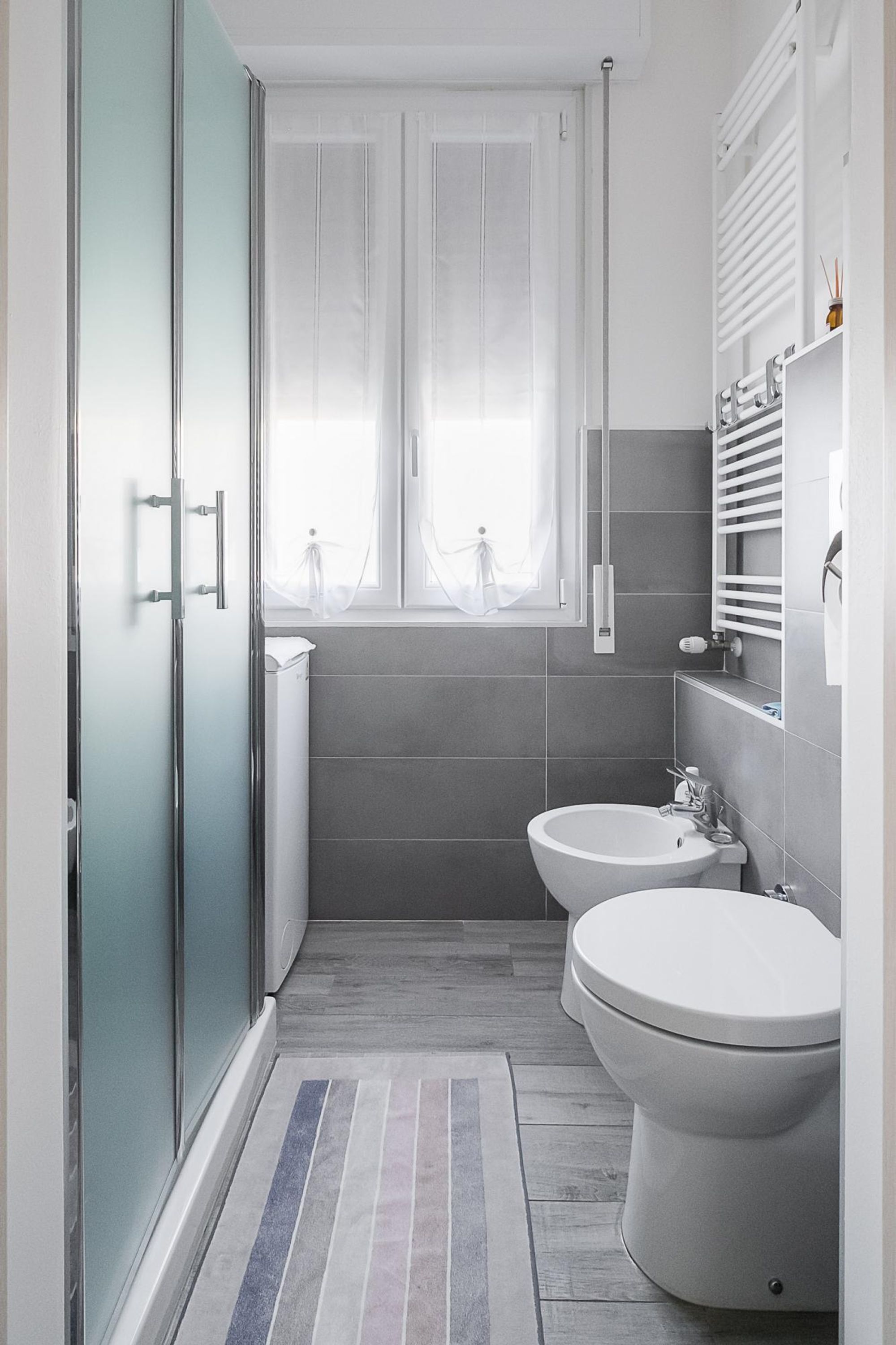 A modern bathroom with a shower, two toilets, and a window.