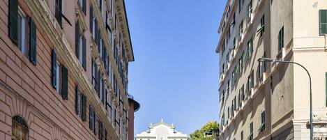 A narrow street flanked by historic buildings with large windows and shutters.