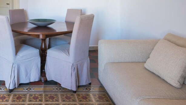 Un coin repas comprenant une table ronde, quatre chaises, un saladier et un climatiseur fixé au mur.