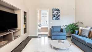 Un saló modern amb televisió de pantalla plana, un sofà, una taula de centre i una planta gran.