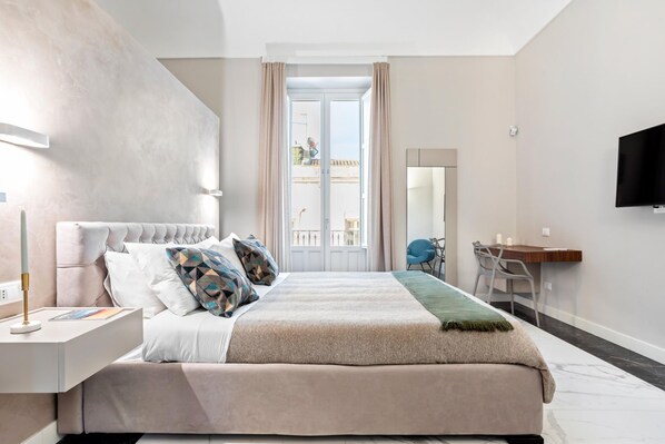 Un dormitorio moderno con una cama grande, un escritorio y un televisor.