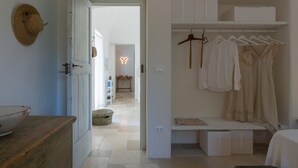 Et værelse med seng, sengebord, skab og en hængende lampe.