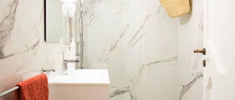 A bathroom with a white sink, a shower with a glass door, a toilet, and a towel rack with a towel.