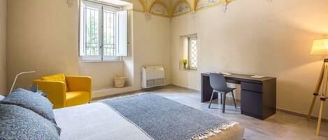 A bedroom with a bed, a desk, a chair, and a window.