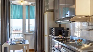 A compact kitchen with a dining area, a built-in oven, and a gas stove. - Casa Rosanna by Wonderful Italy (Genoa)
