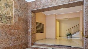 A lobby with a marble wall, a staircase, and a potted plant. - Carignano Design Apartment 7 by Wonderful Italy (Genoa)