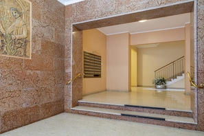 Stairs lead to an upper level with a decorative relief sculpture and a potted plant.