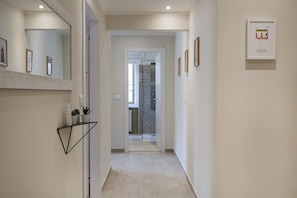 Stylish hallway leads to a room with a patterned shower curtain and framed artwork.