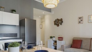 A modern kitchen with a built-in refrigerator, a dining table with chairs, and a sofa in the living area. - Carignano Design Apartment 7 by Wonderful Italy (Genoa)