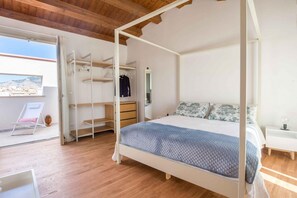 A bedroom with a four-poster bed, a walk-in closet, and a balcony with a chair and cactus.