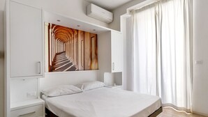A modern bedroom with a large bed, built-in wardrobe, and a unique wooden art piece above the bed. - Cineteca White Studio by Wonderful Italy (Bologna)