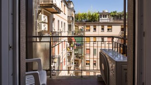 A balcony with a view of adjacent buildings, a white chair, and an air conditioning unit. - Cineteca White Studio by Wonderful Italy (Bologna)