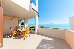 Ein Balkon mit Tisch und Stühlen, der einen herrlichen Blick auf das Meer und die Berge bietet.
