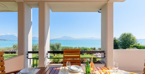 Un balcon avec une table dressée pour le dîner, offrant une vue panoramique sur la mer et les montagnes.
