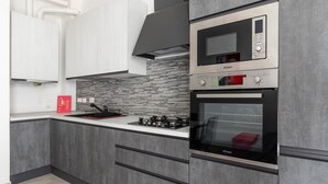 Una cocina moderna con armarios grises, un microondas de acero inoxidable y un horno empotrado.