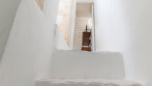 A narrow stairway leading to a room with a stone wall and a wooden ladder. - Olivia in Wonderland by Wonderful Italy (Ostuni)