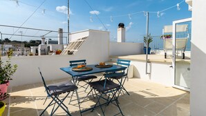 A rooftop terrace with a table and chairs, a view of the city, and string lights. - Olivia in Wonderland by Wonderful Italy (Ostuni)