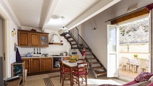 A kitchen with wooden cabinets, a dining table with chairs, a staircase, and a view of the outside. - Salomone Apartment 15 With Terrace by Wonderful Italy (Syracuse)