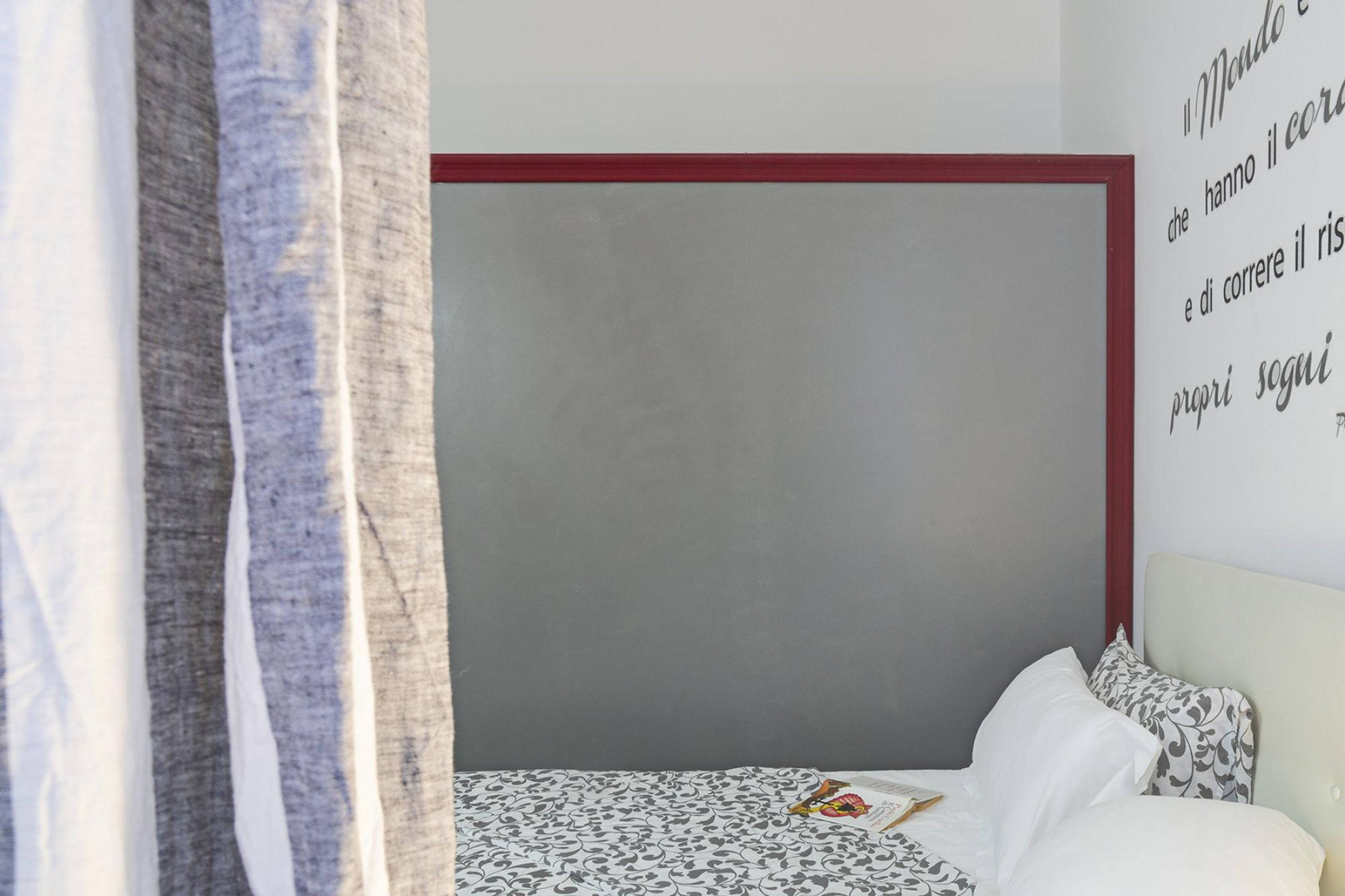 Un dormitorio con cama, una pared con una cita y una cortina.