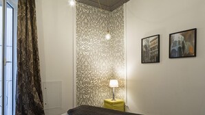 A bedroom with a patterned wallpaper, a bed, a bedside table with a lamp, and two framed pictures on the wall. - La Dimora del Ducale by Wonderful Italy (Genoa)