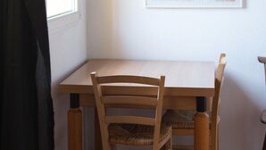 A room with a wooden table and chairs, a framed poster on the wall, and a window with a view of the outside. - Nosadella Mezzanine by Wonderful Italy (Bologna)