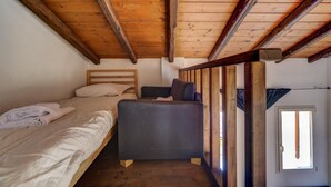 A small, rustic room with a wooden ceiling and a bunk bed with a single bed below. - Nosadella Mezzanine by Wonderful Italy (Bologna)