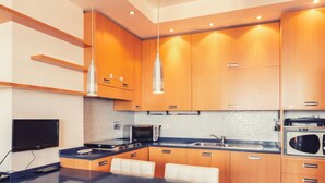 A modern kitchen with wooden cabinets, a stove, a microwave, and pendant lights. - Le Orchidee 10 Apartment by Wonderful Italy (Sanremo)