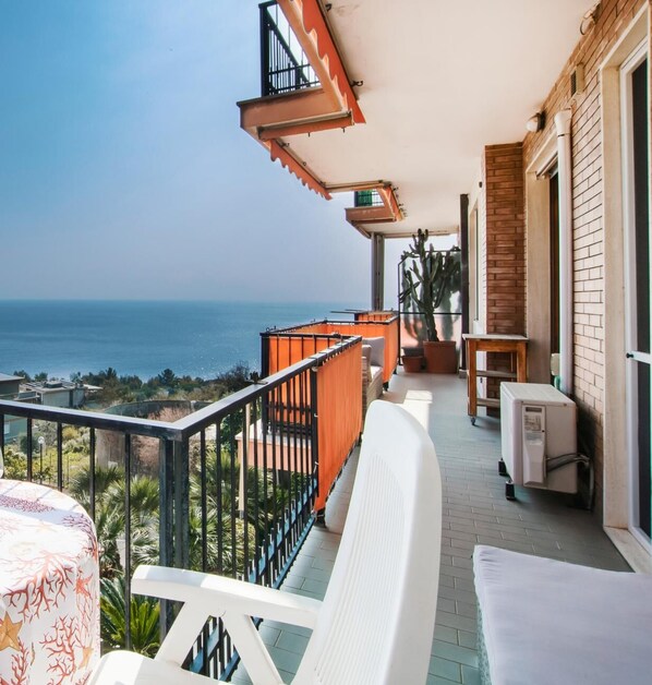 Enjoy the ocean view from this balcony with a chair and table.