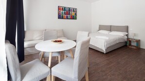 Una habitación de hotel moderna con una cama, una mesita con sillas, un sofá y una obra de arte colorida en la pared.