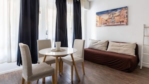 Una habitación moderna con una mesa redonda, dos sillas, un sofá y un cuadro de un paisaje urbano en la pared.