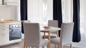Una cocina moderna con armarios blancos, un horno de acero inoxidable y una mesa de comedor con cuatro sillas grises.