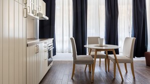 Una cocina moderna con armarios blancos, horno empotrado y comedor con una mesa redonda y cuatro sillas.