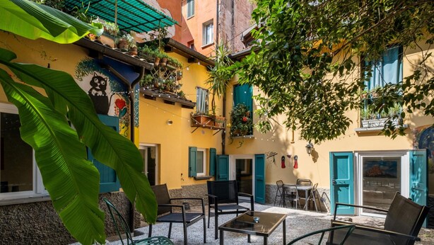 A courtyard with outdoor seating, potted plants, and a mural on the building. - Il Giardino Segreto di Orfeo by Wonderful Italy (Bologna)