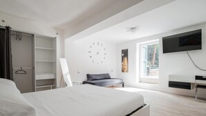 A modern bedroom with a bed, a wardrobe, a desk, a TV, and a large window. - Il Giardino Segreto di Orfeo by Wonderful Italy (Bologna)