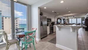 A modern kitchen with a central island, stainless steel appliances, and a dining area with chairs.