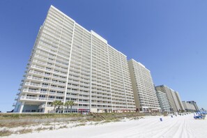 Un hôtel de grande hauteur doté de nombreux balcons, situé près d’une plage au rivage sablonneux.