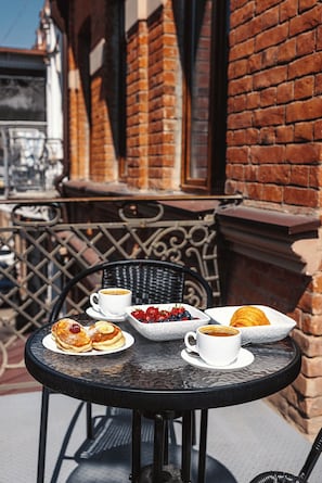 A round table with breakfast items, a cup of coffee, and a basket of fruit. - Boutique Hotel Manufactura (Tbilisi)
