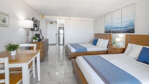 Een hotelkamer met twee bedden, een bureau, een stoel, een koelkast en een televisie.