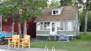 Une petite maison de plain-pied avec un porche, un espace extérieur couvert aménagé en coin salon et une petite terrasse.