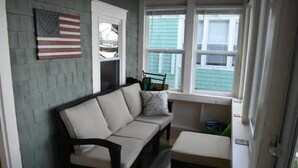 Une pièce confortable avec un canapé, une petite table et une fenêtre donnant sur un immeuble verdoyant.