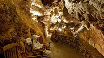 A cave interior with wooden benches and a person sitting.