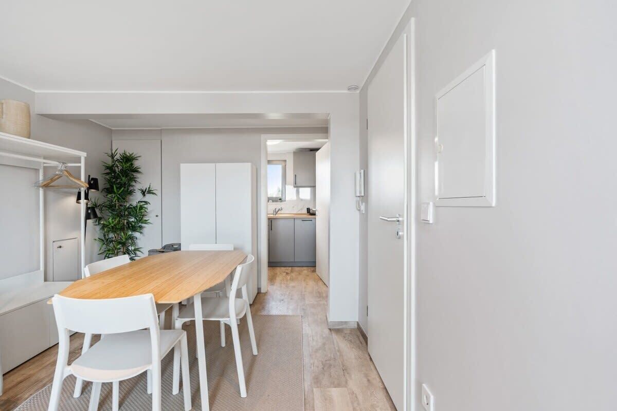 A modern kitchen with white cabinetry, a wooden dining table, and white chairs.