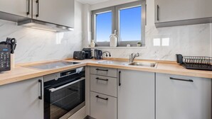Una cocina moderna con horno empotrado, microondas y cafetera.