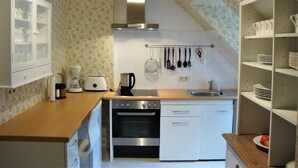 A compact kitchen with a stove, oven, and coffee maker. - Apartment in a half-timbered house 4 km to the ski lift carousel or Rothaarsteig (Winterberg)