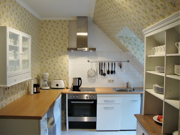 A compact kitchen with a stove, oven, and coffee maker.