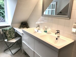 A modern bathroom with a dual sink vanity, a large mirror, and a window providing natural light. - Apartment in a half-timbered house 4 km to the ski lift carousel or Rothaarsteig (Winterberg)