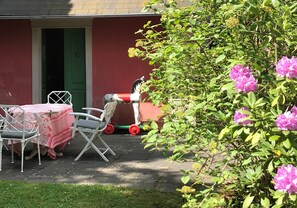 A patio with a table and chairs, a small cart, and a garden with pink flowers. - Apartment in a half-timbered house 4 km to the ski lift carousel or Rothaarsteig (Winterberg)