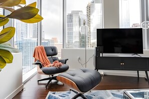 Uma sala de estar moderna com vista para a cidade, um sofá de couro preto, uma TV de tela plana e um rack preto para entretenimento.