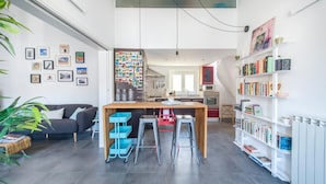Um espaço de estar moderno com cozinha, área de jantar e estante repleta de livros.