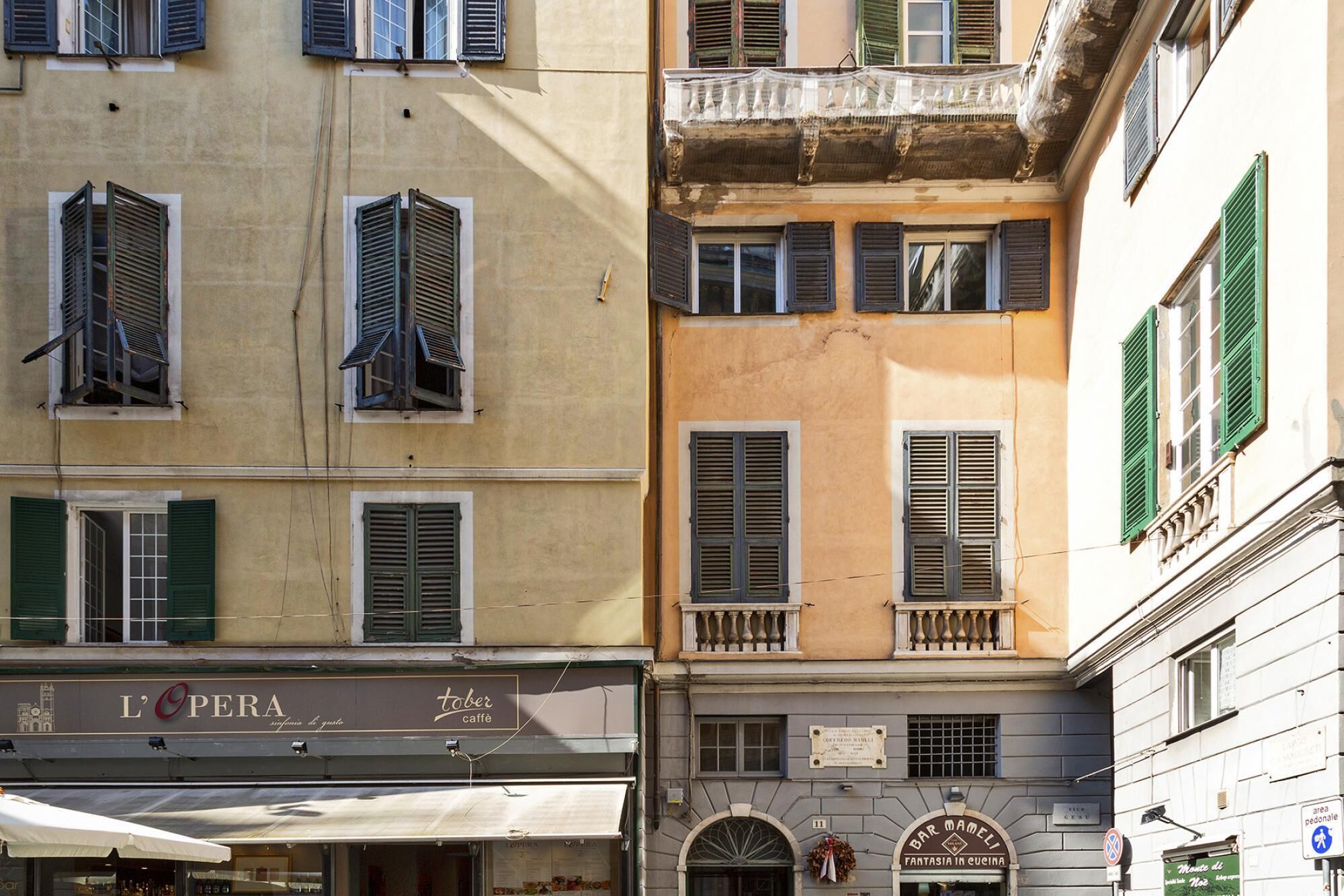 A multi-story building with various shops on the ground floor, including a café named 'L'OPERA'.